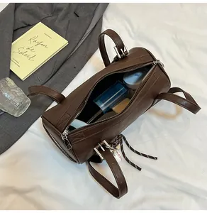 Detailansicht der dunkelbraunen Zylindertasche mit Innenraum und Baseball-Anhänger-Detail