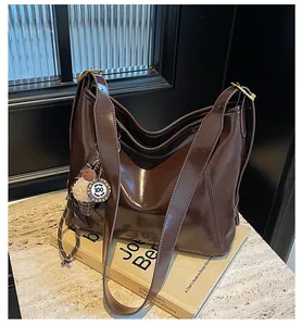 Macro shot of dark brown polished leather tote bag with ice cream charm and gold hardware