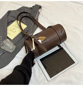 Nahaufnahme der braunen Zylindertasche mit geprägten Buchstaben und Baseball-Anhänger
