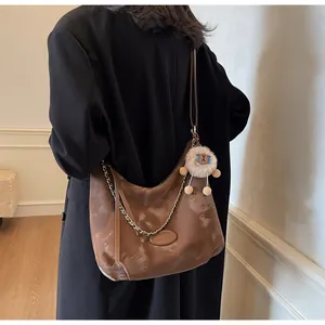 Detail view of large brown crescent tote bag with glossy finish and metal chain