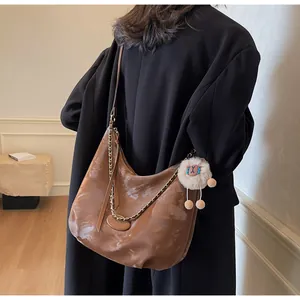 Detail of vintage brown leather hobo bag with gold chain and plush charm accessory