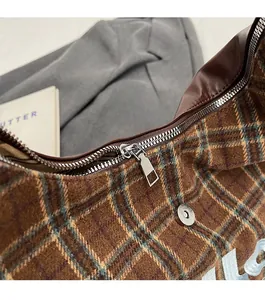 Detail of smooth silver metal zipper on vintage plaid fabric shoulder bag with leather trim