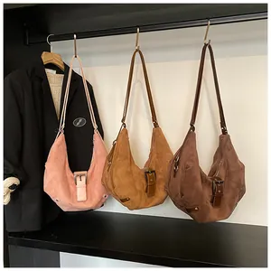 Detailed texture of suede hobo bags in pink, yellow, and brown on a black rack