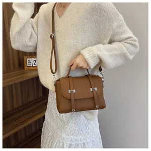 Close-up of brown vintage crossbody bag with vertical strap details and silver hardware