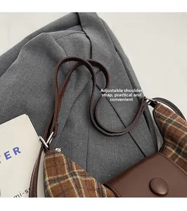 Detail of adjustable leather strap and silver buckle on plaid vintage shoulder bag