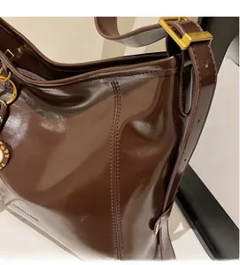 Detailed view of dark brown glossy leather texture and vintage gold metal buckle hardware