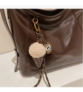 Detail of dark brown wax leather tote bag featuring a plush ice cream cone charm