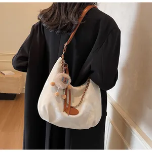 Detail of white pleated cloud tote bag with brown leather strap and plush charm