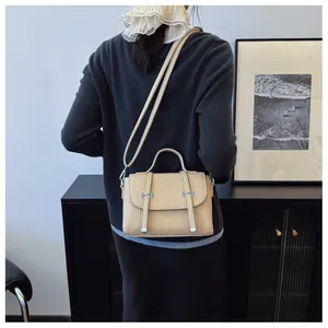 Detailed back view of model wearing apricot textured crossbody bag with vertical stripes