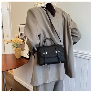 Vertical embossed black crossbody bag with silver buckles and adjustable strap on model