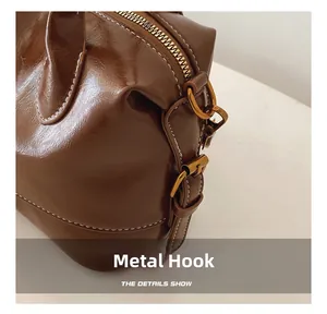 Close-up of vintage bronze hardware and white stitching on a brown leather handbag