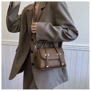 Detail of dark brown pleated crossbody bag with silver buckles and a retro flap design