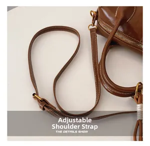 Detail view of adjustable shoulder strap and gold hardware on dark brown vintage bag