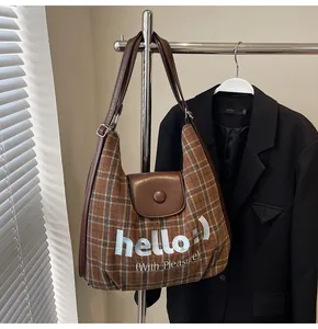 Detailed view of brown checkered hobo bag with leather strap and white hello print
