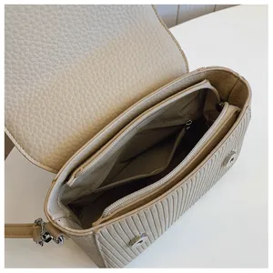Detail of crossbody bag interior with multi-layer compartments and magnetic silver buckle