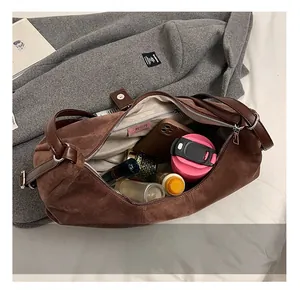 Spacious interior of dark brown suede cylindrical shoulder bag with daily essentials