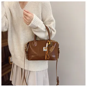 Close-up of brown vintage pillow bag with contrast stitching and golden abacus charm