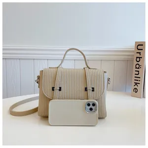 Detailed view of the vertical stripe texture and silver metal buckles on the cream crossbody bag