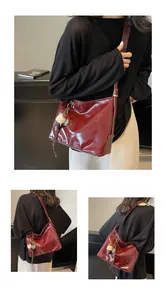 Close-up of deep red glossy faux leather tote bag with stylish plush pendant detail