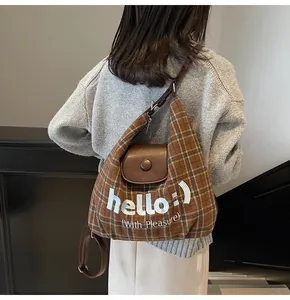 Detail of vintage brown plaid crossbody bag with hello print and leather flap