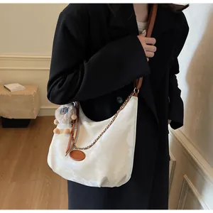 Detail of cream tote bag featuring brown leather strap and cute plush sheep charm