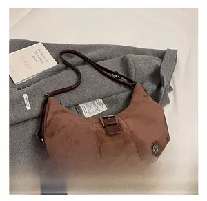 Detail of brown suede hobo bag with vintage metal buckle on a grey coat background