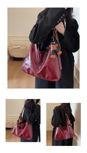 Close-up of glossy burgundy patent leather tote bag with unique cat charm detail