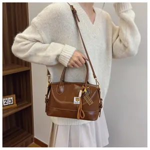 Detail view of dark brown vintage Boston bag with gold abacus pendant and adjustable strap