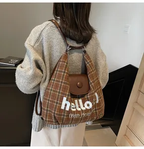 Detail of checkered tote bag featuring white 'hello' embroidery and leather flap cover