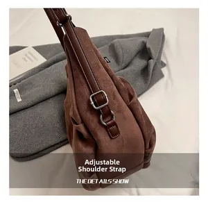 Detail of adjustable shoulder strap with silver buckle on brown suede crossbody bag