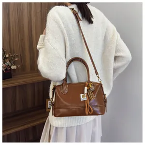 Brown vintage pillow bag detail with decorative abacus pendant and woven strap charm