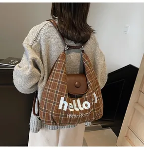 Close-up of retro plaid shoulder bag featuring leather flap and hello embroidery