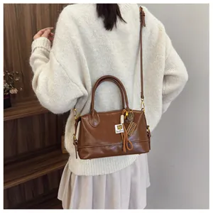 Detail of vintage brown leather Boston bag showing the handle and golden abacus charm