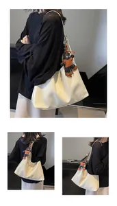 Detail of cream white oversized hobo tote bag featuring a cute black cat plush pendant