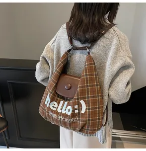 Detail of vintage brown plaid bag with white embroidery and dark leather flap