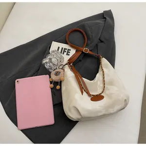 Detail of creamy white marble tote bag with brown leather strap and gold chain accent