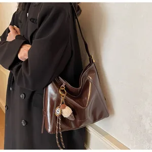 Close-up of dark brown glossy hobo bag with unique ice cream metal pendant charm