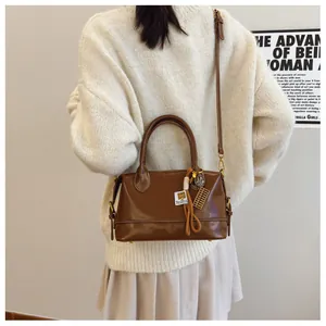 Retro brown leather Boston bag with a wooden abacus charm shown on a crossbody strap