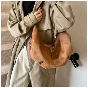 Detail of a large brown suede hobo bag with a metallic buckle and decorative studs