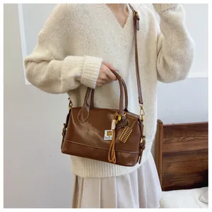 Detail of brown vintage Boston bag with tassels and golden abacus charm decoration