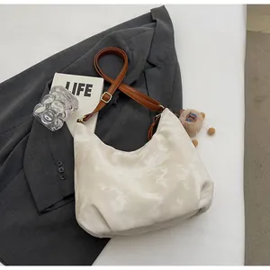 Detail of a white satin tote bag featuring marble print texture and a brown plush bear charm