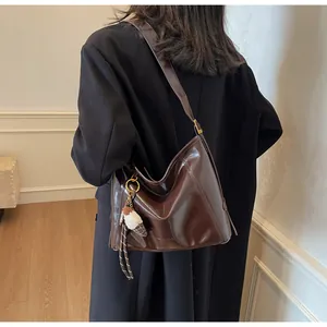Detail of dark brown glossy hobo bag with stitching and ice cream charm