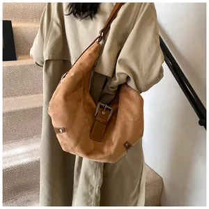 Close-up of brown suede hobo bag featuring deep brown leather trim and metallic buckle