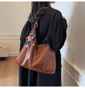 Brown high-gloss hobo shoulder bag featuring a cute cat pendant on model with black blazer