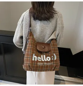 Detail of checkered tote bag with leather flap and 'hello :)' embroidery on textured wool