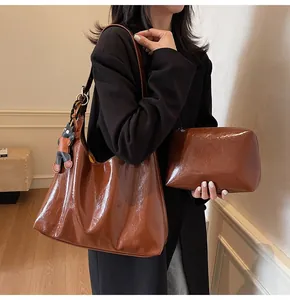 Detail of brown glossy leather tote bag set with cat charm and inner zipper pouch