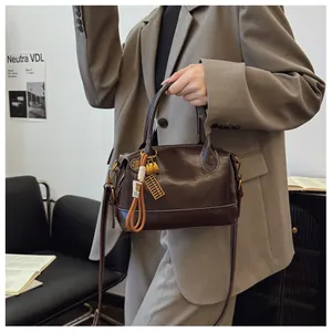Detail of dark brown leather handbag with contrast stitching and golden abacus charm