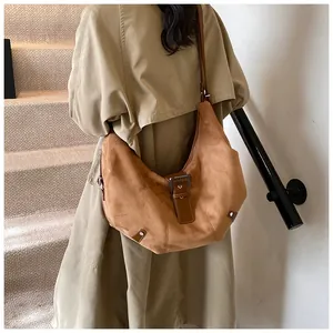 Detail of vintage brown suede hobo bag with belt buckle and textured finish on a model