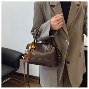 Detail of vintage coffee brown boston bag with golden abacus charm and leather strap