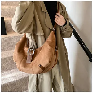 Detail of tan suede shoulder bag with silver metallic buckle on an autumn trench coat